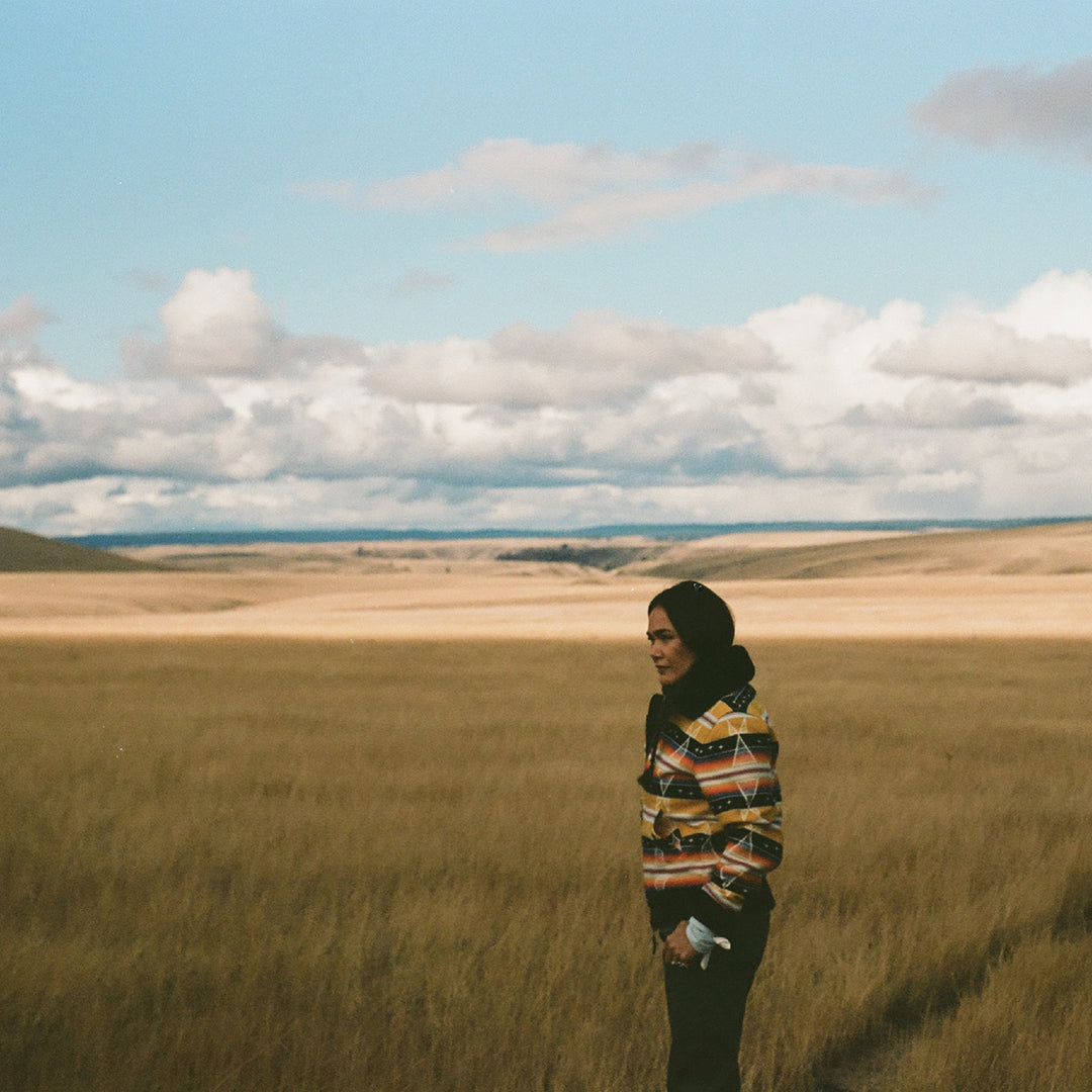 Native American model wearing yellow wool coat in field
