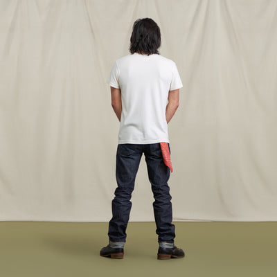 Male model in selvedge denim, a white tshirt and red bandana in his back pocket.