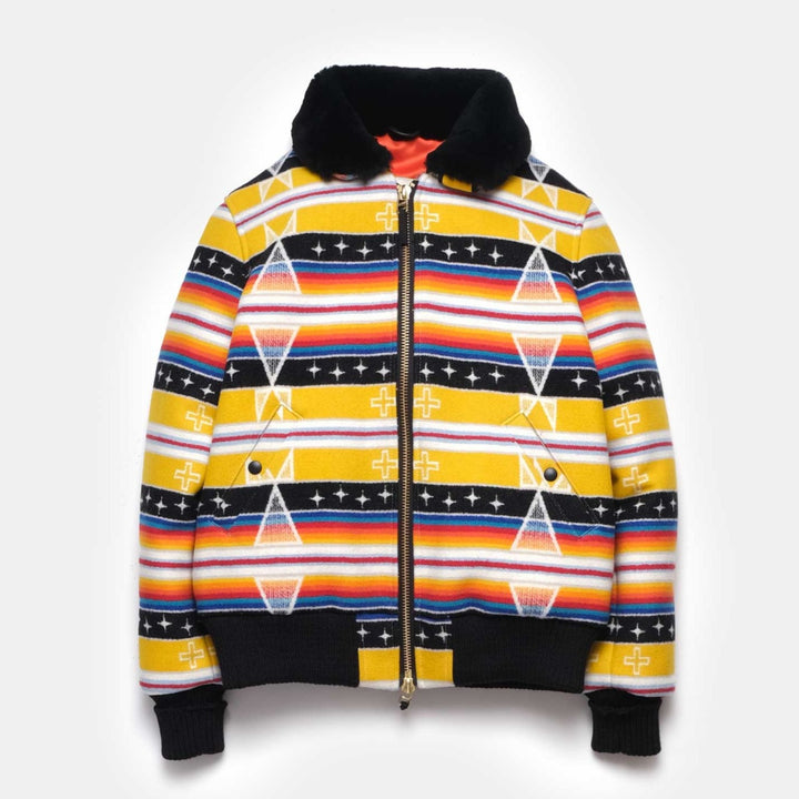 The yellow and black printed Ginew + Dehen Facing East Flyer's Jacket is laid flat on a white background. The Jacket features black cuffs and trim at the hem and neck, a full length zipper, and an orange inner lining.