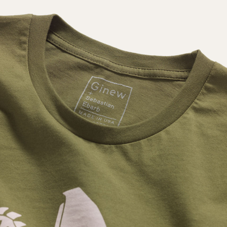 Close up of printed tag on inside of back of shirt. Tag reads: "Ginew + Sebastian Ebarb / Made in USA"