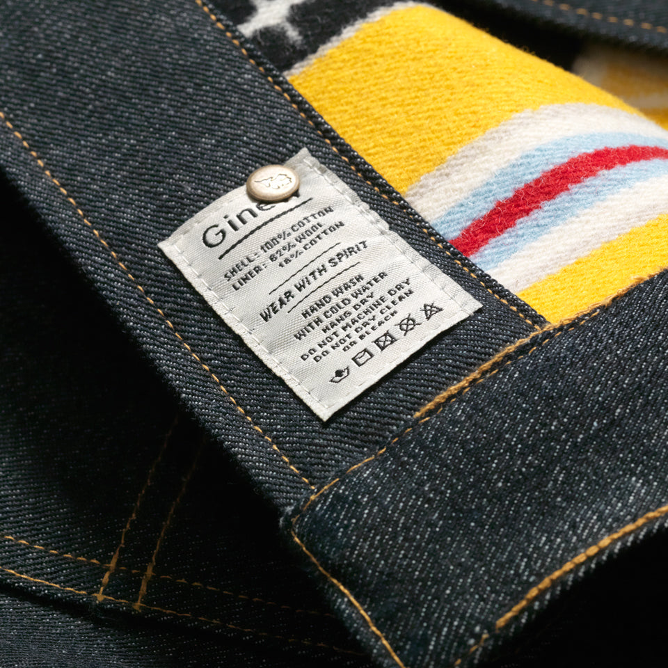 Close up of Heritage Coat open to show a white tag on the inner right side seam with the word "Ginew" and care instructions.