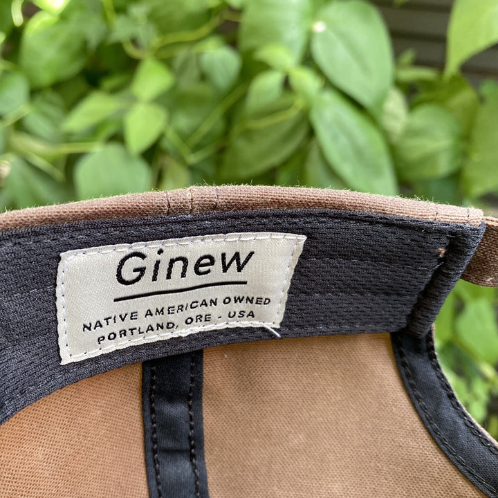 Detail image of the brand tag in the hat band. Tag text says "Ginew Native American Owned Portland, ORE - USA"