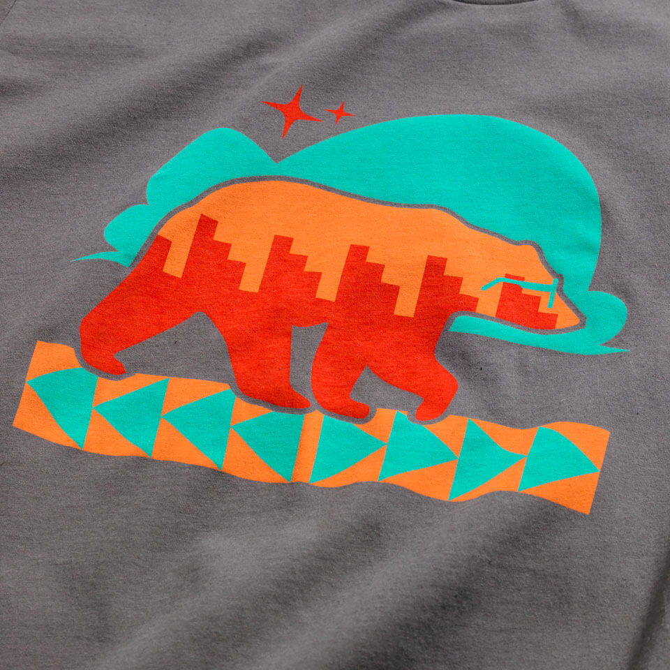 A grey tee shirt with Naasgo/Forward movement bear print in turquoise, orange, and red ink is shown on a male model standing in front of a neutral background.