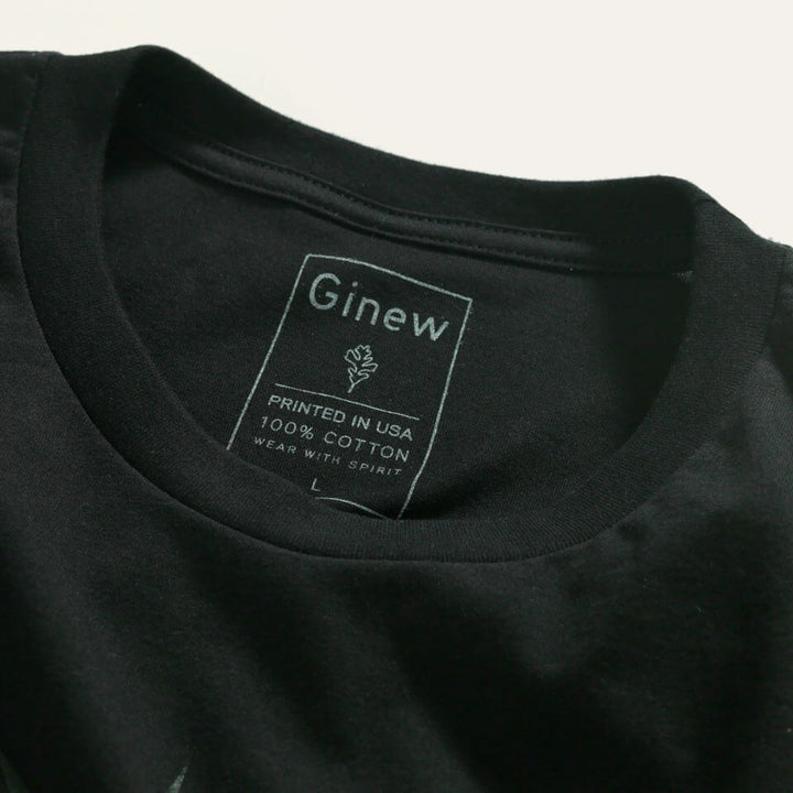 Close up of printed tag inside the back of the tee which reads: "GINEW - PRINTED IN USA - 100% COTTON - WEAR WITH SPIRIT"