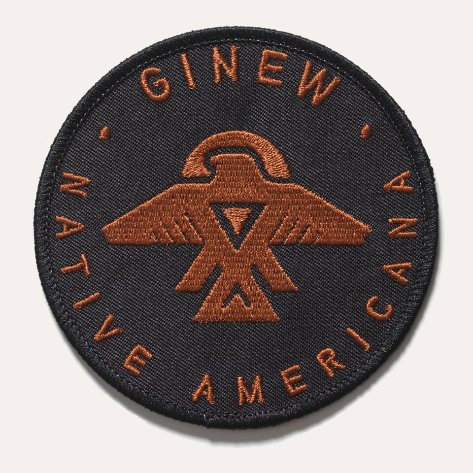 Ginew Native Americana text with thunderbird symbol in copper embroidery on black twill sew  on circle patch.