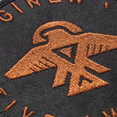 Thread details of thunderbird symbol in copper embroidery on black twill sew  on circle patch.