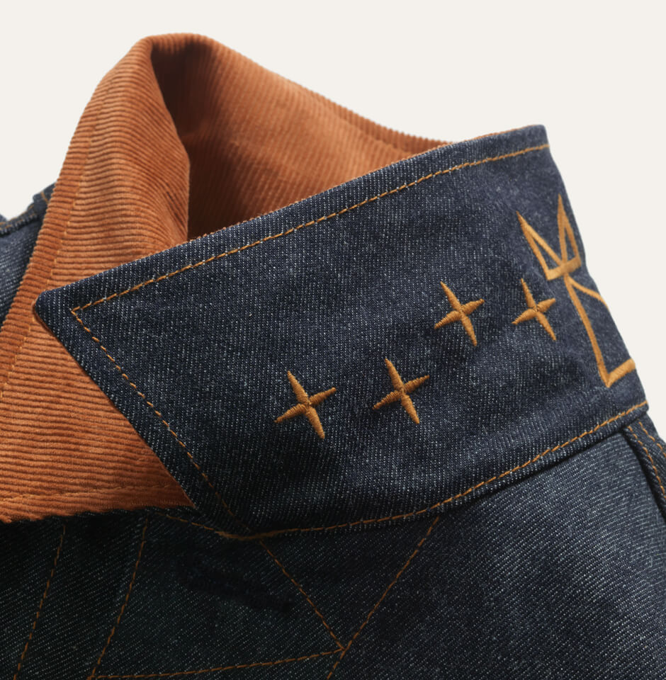 View of under the collar which features custom stitching under the corduroy collar, stitching is a bronze-brown color. It echoes the symbolism of the Ginew® + Dyani White Hawk “Facing East” design.