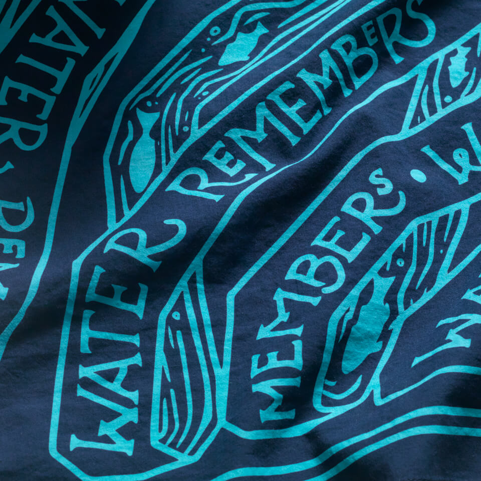 Navy bandana with aqua blue screen printing design with the words "water remembers" and fish