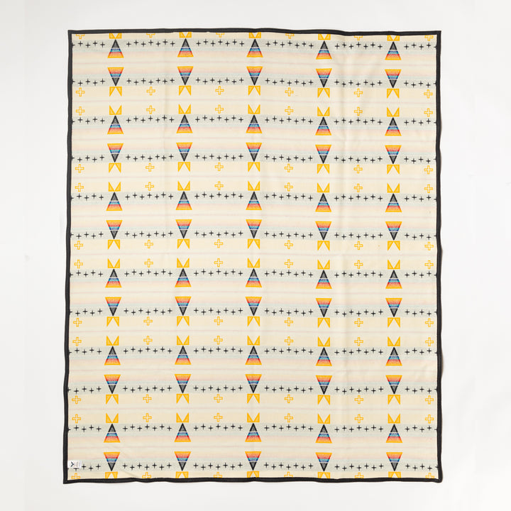 The backside of the Facing East wool blanket. A yellow, black, white, red, and blue wool blanket features a diamond pattern. Shown laid flat against a white background.