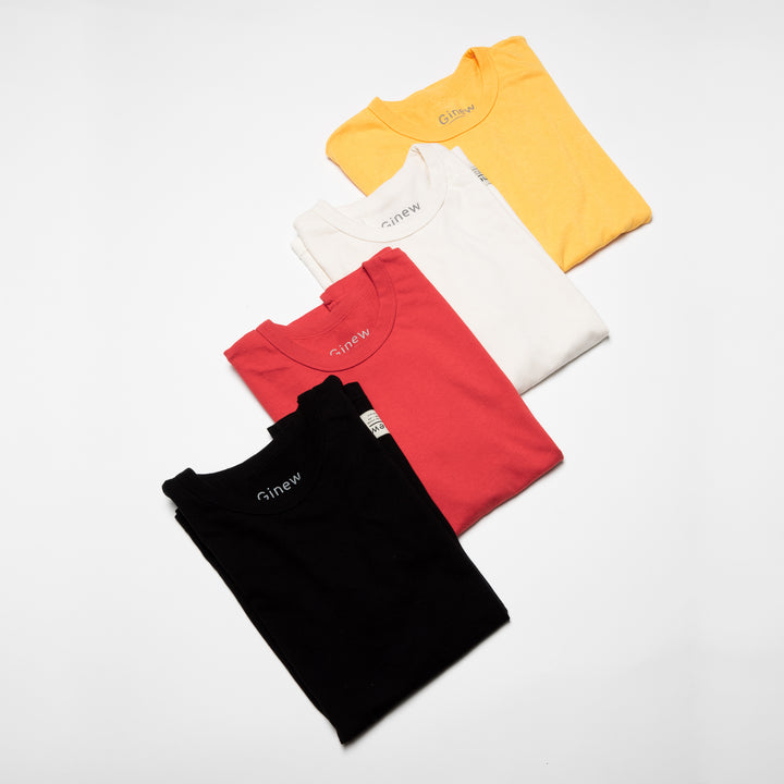 Four Crew Tees in Marigold yellow, Arctic Wolf white, Urban Red, and Jet Black are folded and laid in a diagonal position across a white background.