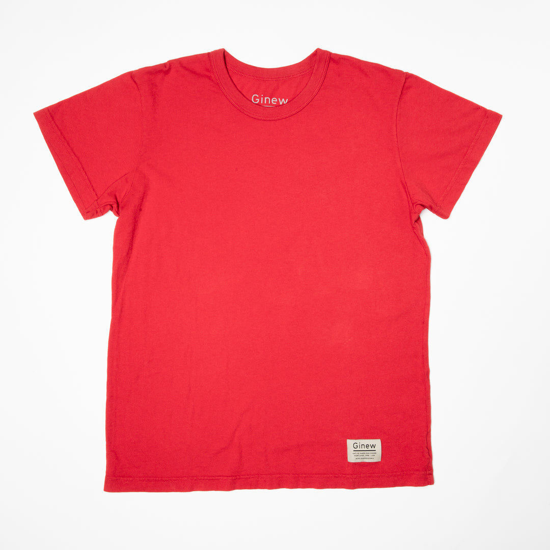 A crew t-shirt in an urban red color is laid flat on a white background. The shirt has a white tag at the bottom left hem with the word Ginew on it.