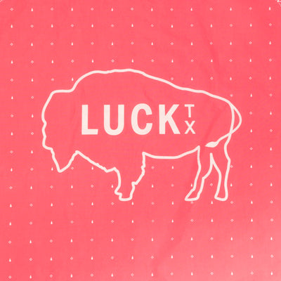 coral pink bandana with white design of an outline of a buffalo and the words Luck TX