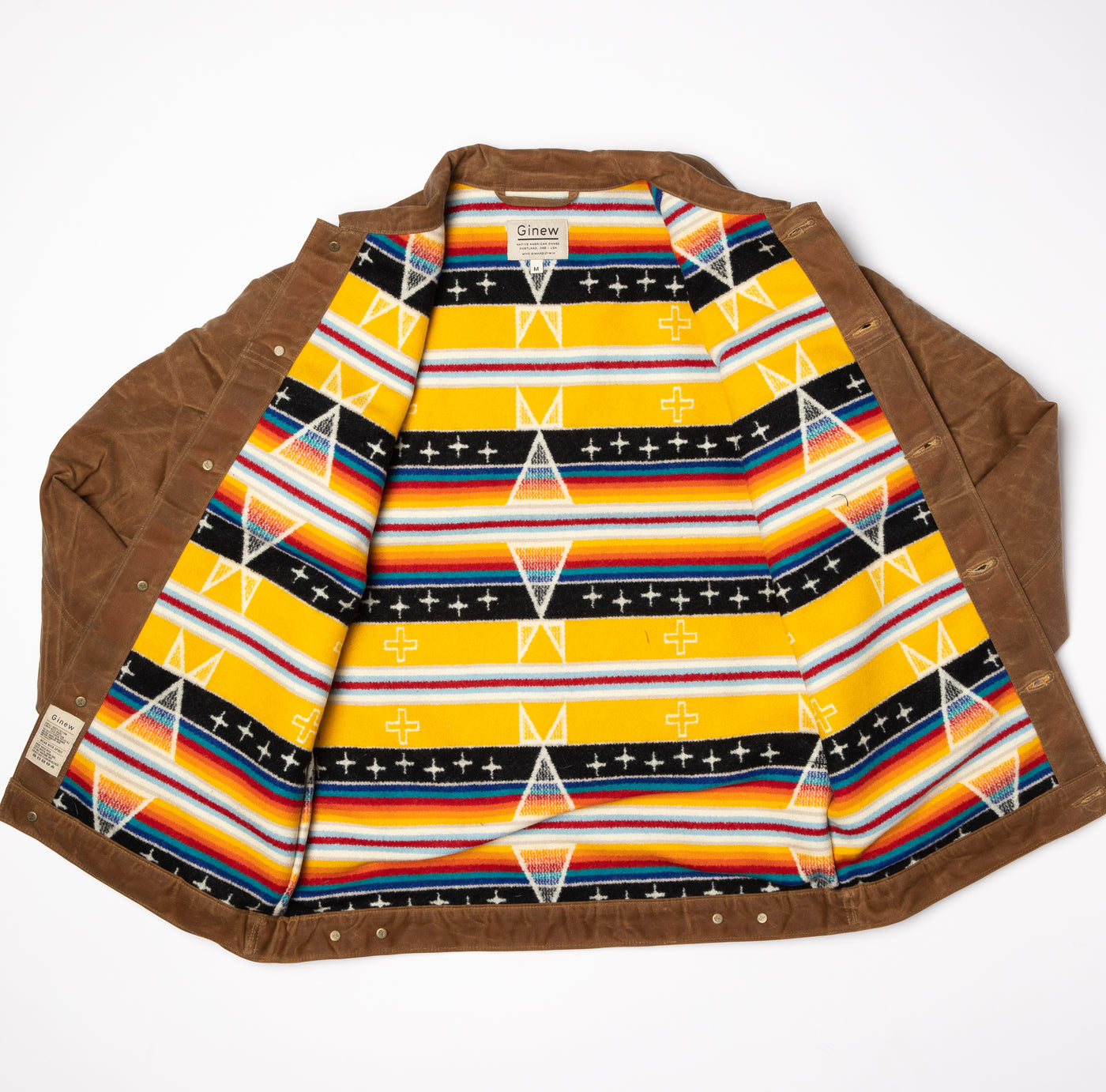 Full view of Wax Rider Coat in Brown. Both sides lay opened to the Facing East lining on the inside. Coat on a neutral Background.