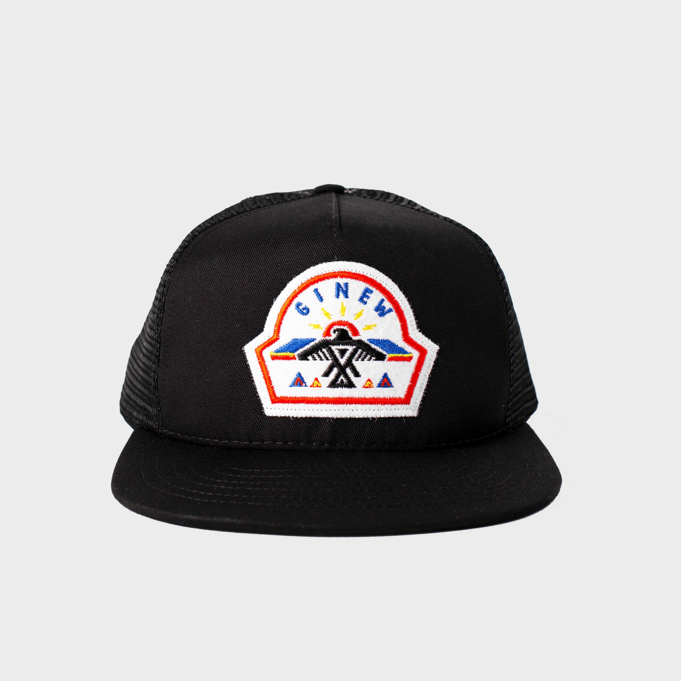 A black Trucker Hat with a white Ginew patch sewn at center front is shown on a white background. The patch features a thunderbird design stitched from blue, black, red, yellow, and orange thread.